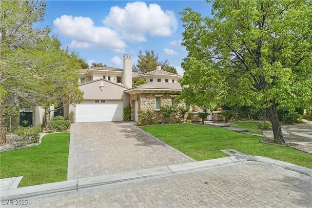 view of front of home featuring decorative driveway, stone siding, an attached garage, a front yard, and stucco siding