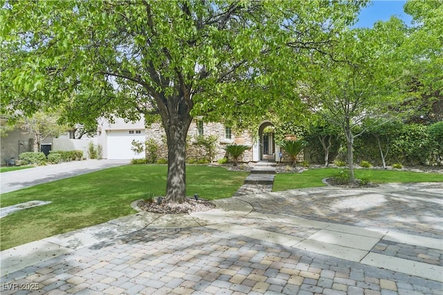 view of property hidden behind natural elements featuring a garage, a front lawn, and concrete driveway