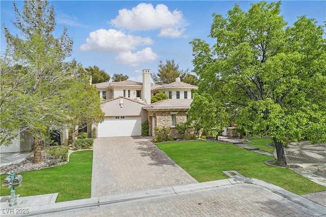 view of front of home with stone siding, a chimney, an attached garage, a front yard, and decorative driveway