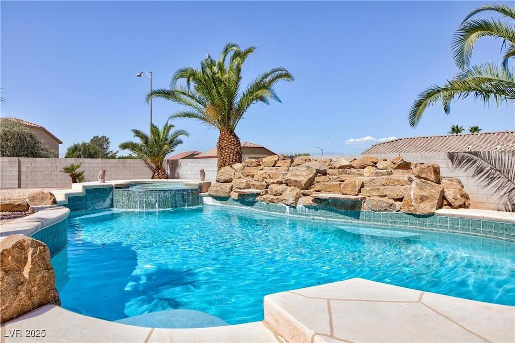 view of pool featuring a fenced backyard and a pool with connected hot tub