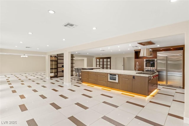 kitchen featuring a spacious island, open floor plan, visible vents, modern cabinets, and built in fridge