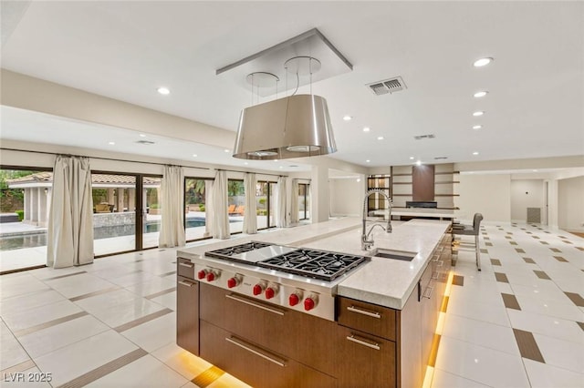 kitchen featuring stainless steel gas stovetop, open floor plan, visible vents, and a sink
