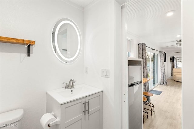 bathroom featuring crown molding, wood finished floors, toilet, and vanity
