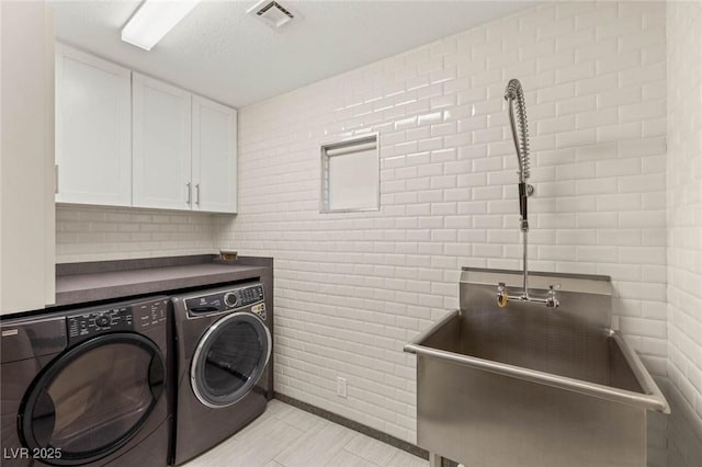 laundry room featuring separate washer and dryer, visible vents, and cabinet space