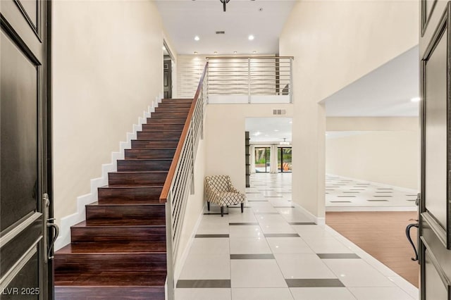 stairway featuring recessed lighting, visible vents, tile patterned flooring, and baseboards