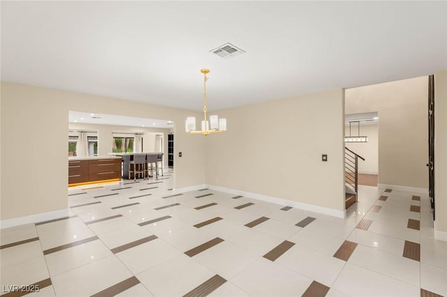 spare room with a chandelier, stairway, visible vents, and baseboards