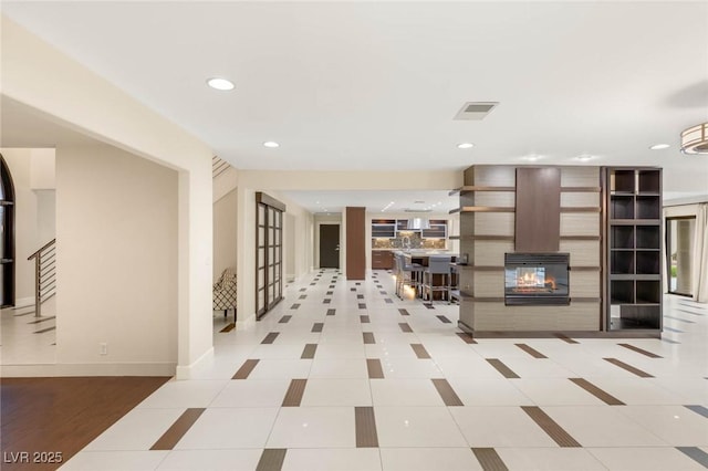 corridor with baseboards, visible vents, recessed lighting, and light tile patterned floors