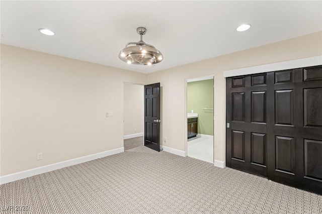 unfurnished bedroom featuring baseboards, carpet flooring, ensuite bathroom, and recessed lighting