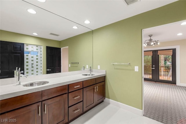 bathroom featuring visible vents, baseboards, a sink, and french doors