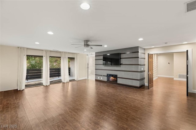 unfurnished living room featuring a glass covered fireplace, wood finished floors, visible vents, and ceiling fan