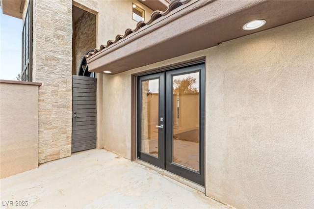 doorway to property with a patio, french doors, and stucco siding