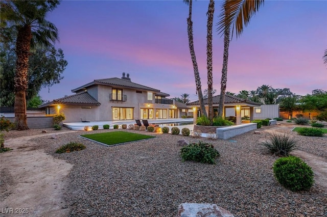 view of front of house featuring a tile roof, a chimney, a patio area, and stucco siding