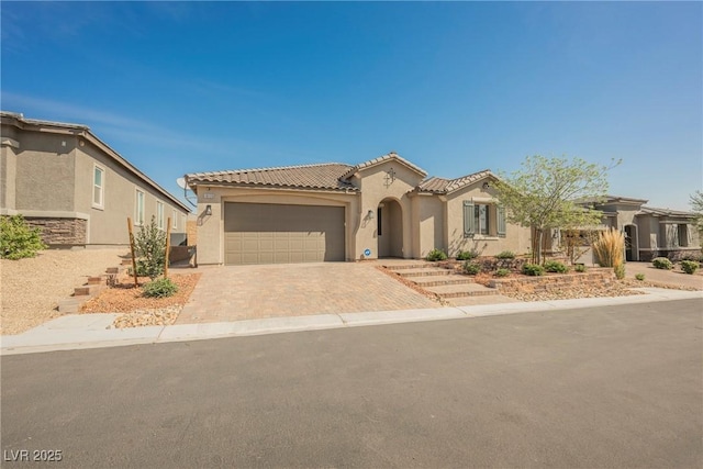 mediterranean / spanish house with an attached garage, stucco siding, driveway, and a tile roof