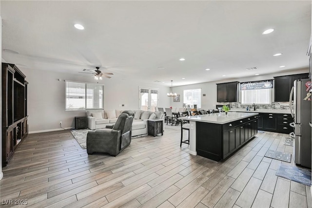 10126 Cliff Dwellings Ave, Las Vegas, NV 89178 - kitchen with a kitchen bar, light countertops, ceiling fan, dark cabinetry, and open floor plan
