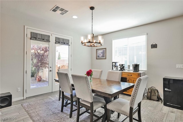 dining room with visible vents, light wood-type flooring, baseboards, and an inviting chandelier