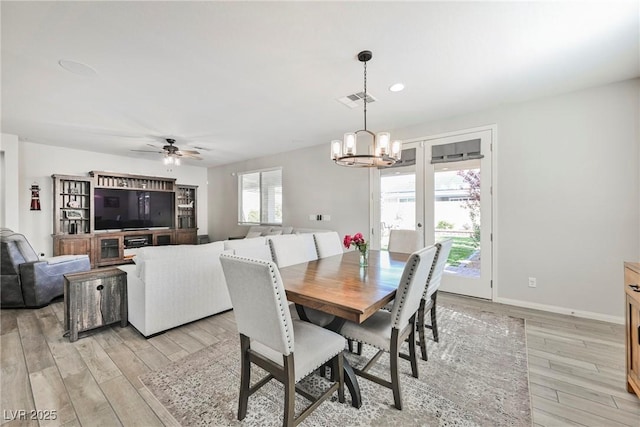 dining area featuring light wood-style floors, baseboards, ceiling fan with notable chandelier, and visible vents