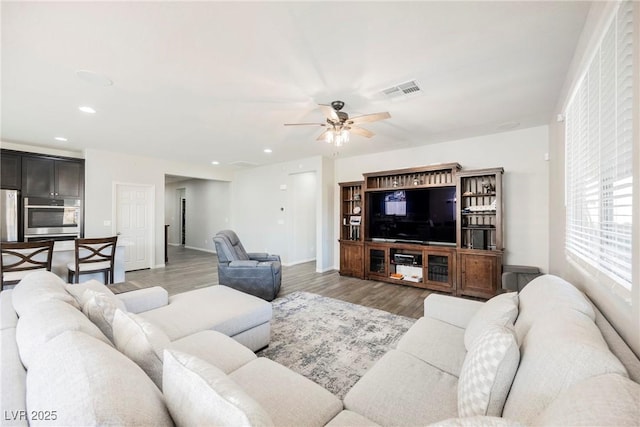 living room with light wood-style floors, a ceiling fan, baseboards, recessed lighting, and visible vents