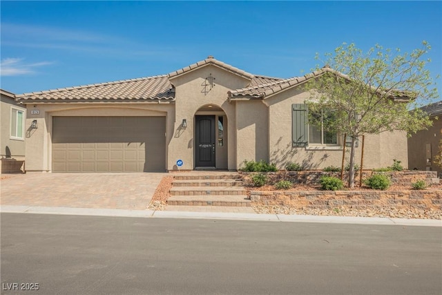 mediterranean / spanish home with a garage, stucco siding, driveway, and a tile roof
