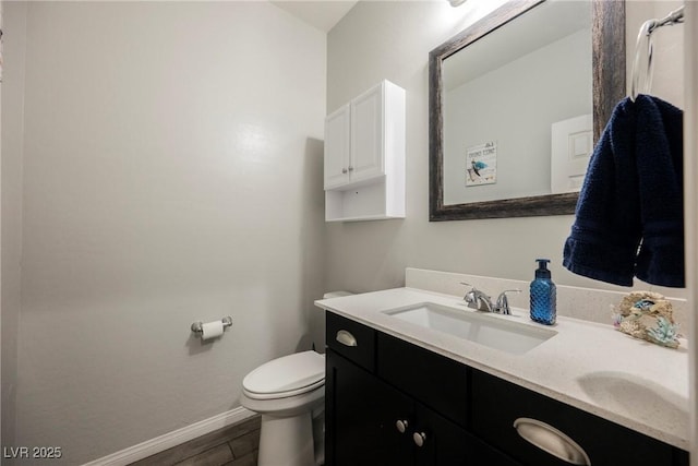bathroom with vanity, baseboards, toilet, and wood finished floors