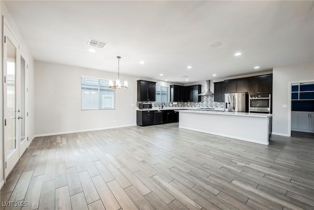 10126 Cliff Dwellings Ave, Las Vegas, NV 89178 - kitchen featuring stainless steel appliances, wall chimney exhaust hood, light countertops, a chandelier, and backsplash