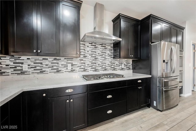10126 Cliff Dwellings Ave, Las Vegas, NV 89178 - kitchen featuring wall chimney exhaust hood, stainless steel appliances, light wood-style floors, and backsplash