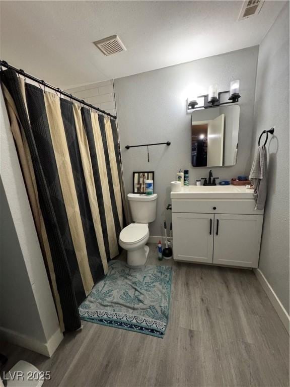 full bathroom featuring toilet, baseboards, visible vents, wood finished floors, and vanity