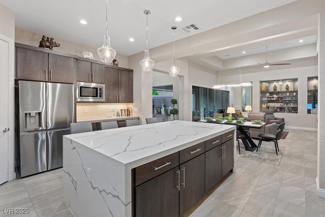 10018 Regency Square Ave, Las Vegas, NV 89148 - kitchen featuring appliances with stainless steel finishes, a kitchen island, dark brown cabinets, pendant lighting, and backsplash