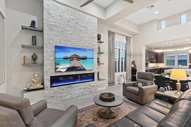 10018 Regency Square Ave, Las Vegas, NV 89148 - living area featuring a stone fireplace, healthy amount of natural light, a towering ceiling, and ceiling fan