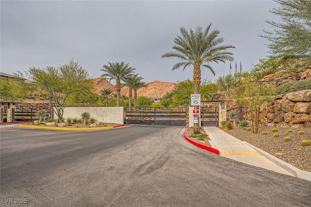26 Sun Mirage Ave, Henderson, NV 89011 - view of road featuring a mountain view, a gate, a gated entry, traffic signs, and curbs