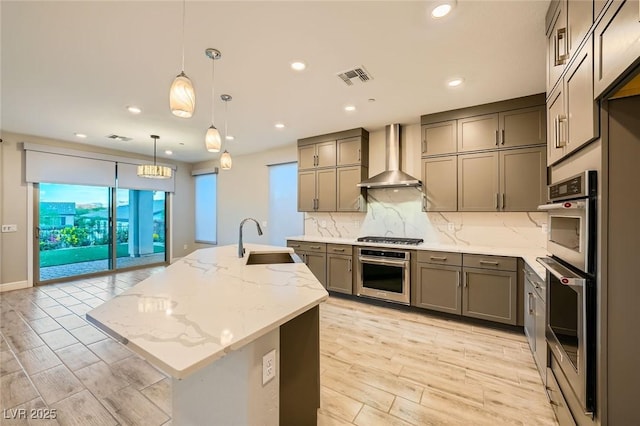 26 Sun Mirage Ave, Henderson, NV 89011 - kitchen featuring a sink, light wood-style floors, backsplash, wall chimney range hood, and an island with sink
