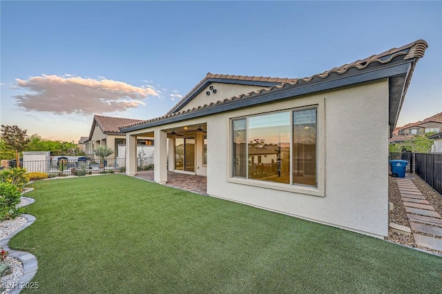 26 Sun Mirage Ave, Henderson, NV 89011 - back of property with a fenced backyard, a tiled roof, stucco siding, a patio, and a lawn