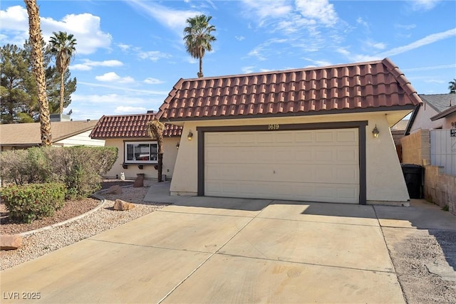 mediterranean / spanish house with concrete driveway, a tiled roof, an attached garage, fence, and stucco siding