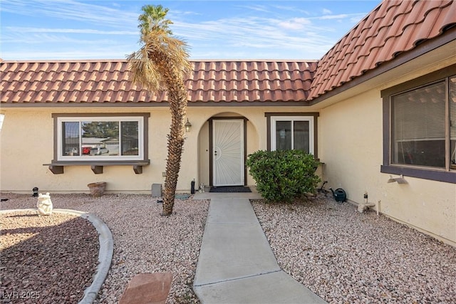 entrance to property featuring stucco siding and a tiled roof