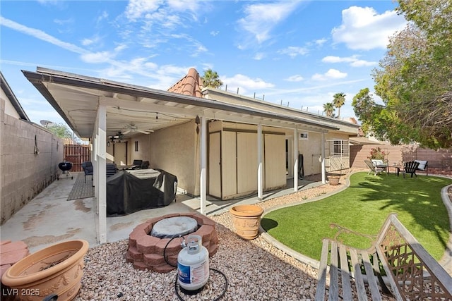 back of house featuring a patio area, a lawn, an outdoor fire pit, a fenced backyard, and stucco siding