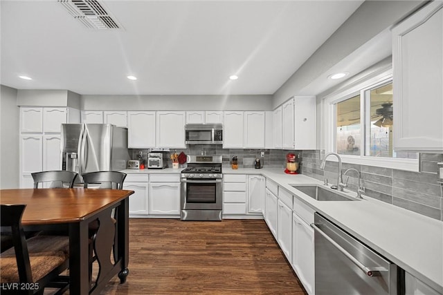 kitchen with stainless steel appliances, a sink, visible vents, decorative backsplash, and light countertops