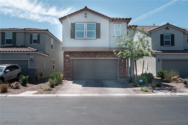 view of front of property with an attached garage, a tiled roof, stucco siding, and decorative driveway