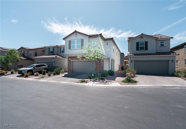 view of front of home featuring a garage, driveway, stone siding, and stucco siding