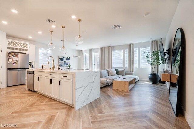 kitchen featuring baseboards, stainless steel appliances, visible vents, and a sink