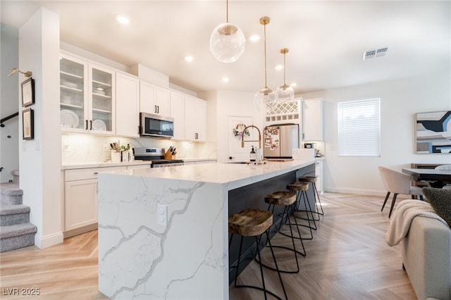 kitchen with white cabinets, visible vents, stainless steel appliances, and a sink