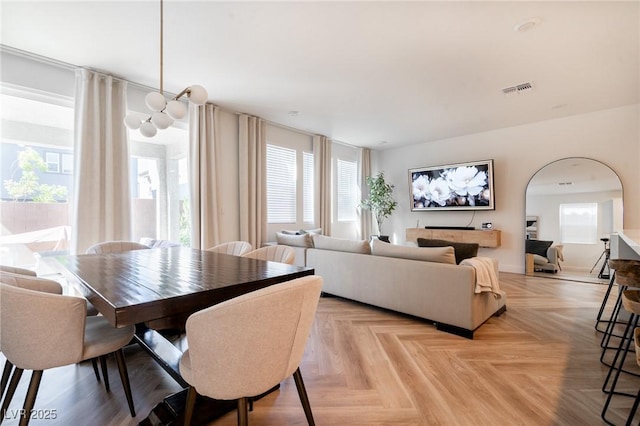 dining space featuring arched walkways, a wealth of natural light, and visible vents