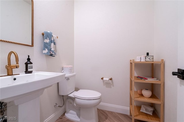 bathroom with wood finished floors, toilet, baseboards, and a sink