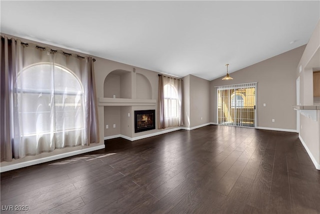7950 W Flamingo Rd Unit 2019, Las Vegas, NV 89147 - unfurnished living room with lofted ceiling, baseboards, a glass covered fireplace, and dark wood-type flooring