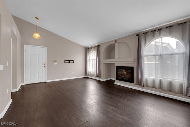 7950 W Flamingo Rd Unit 2019, Las Vegas, NV 89147 - unfurnished living room with lofted ceiling, a glass covered fireplace, dark wood-type flooring, and baseboards