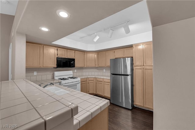 7950 W Flamingo Rd Unit 2019, Las Vegas, NV 89147 - kitchen with light brown cabinetry, freestanding refrigerator, white gas stove, black microwave, and tile countertops
