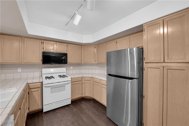 7950 W Flamingo Rd Unit 2019, Las Vegas, NV 89147 - kitchen with light brown cabinetry, gas range gas stove, freestanding refrigerator, black microwave, and tile countertops