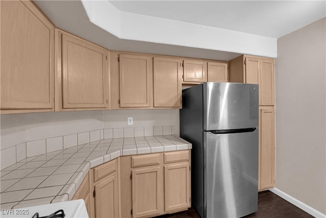 7950 W Flamingo Rd Unit 2019, Las Vegas, NV 89147 - kitchen with tile counters, freestanding refrigerator, light brown cabinetry, and dark wood finished floors