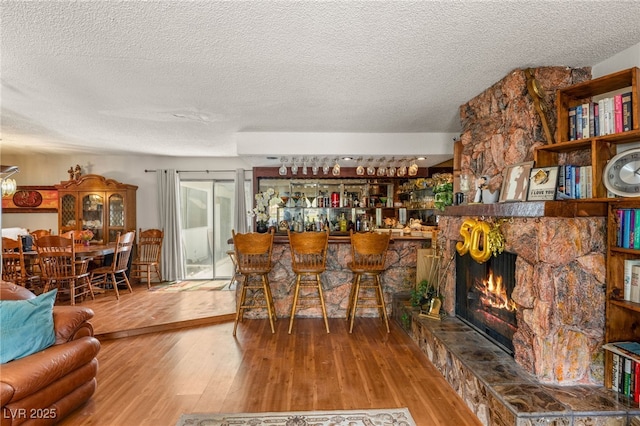 bar with wood finished floors, a textured ceiling, and a fireplace