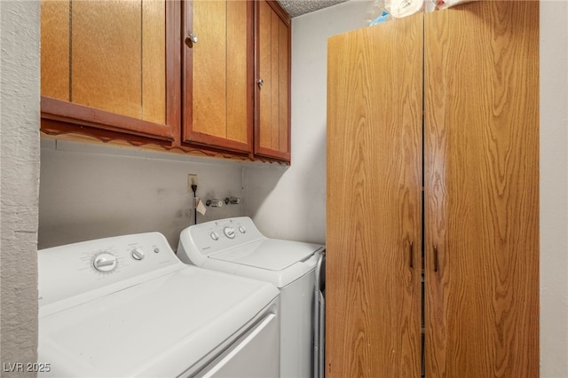 laundry room featuring washing machine and clothes dryer, a textured ceiling, and cabinet space