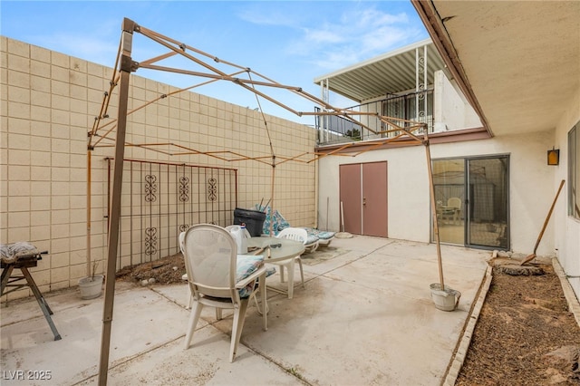 view of patio featuring fence and a balcony