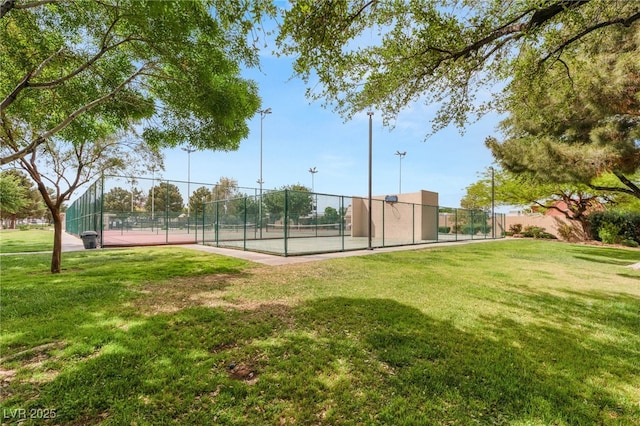 exterior space with fence, a lawn, and a tennis court